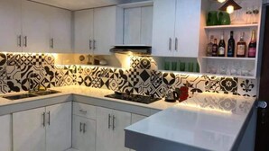 Een moderne keuken met witte kastjes, een zwart-wit tegelpaneel en een ingebouwde wijnrek.