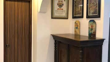 Um corredor com uma porta de madeira, um armário escuro de madeira e três obras de arte emolduradas na parede.