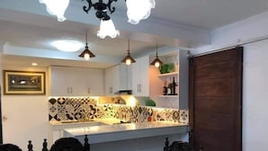 Een keuken met een decoratieve spatwand, hanglampen en een eethoek met een houten tafel en stoelen.