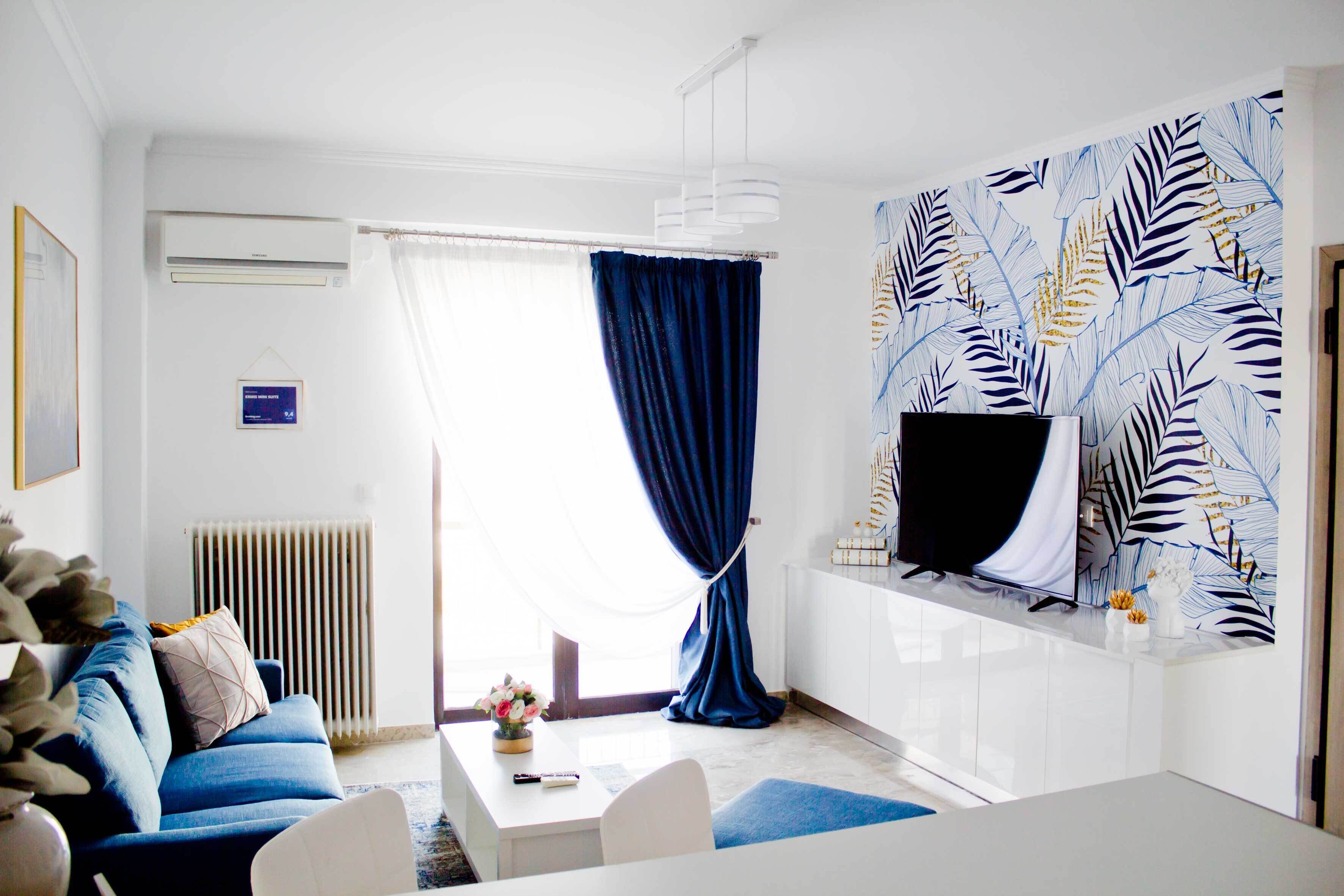 Una sala de estar moderna con un sofá azul, una mesa de centro blanca y un televisor montado en la pared.