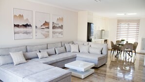 Una sala de estar moderna con un sofá seccional, una mesa de centro y un comedor con sillas.