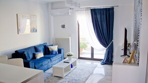 Una sala de estar moderna con un sofá azul, una mesa de centro blanca y un amplio ventanal con cortinas azules.