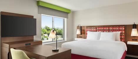 A hotel room with a bed, a desk, a chair, a television, and a window with a view.