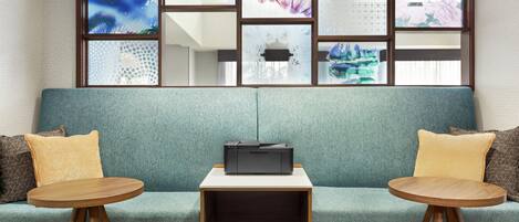 Et moderne værelse med en teal farvet sofa, to træsideborde og en sort printer.