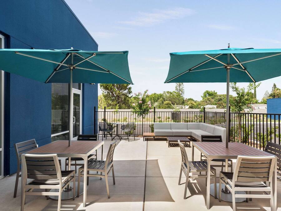 Un patio al aire libre con una mesa, sillas, dos sombrillas y un banco integrado.