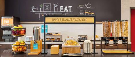 A breakfast buffet area with various food items and a sign that reads "HAPPY BREAKFAST STARTS HERE".