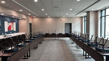 Un salón de conferencias con largas mesas, sillas y piso alfombrado.