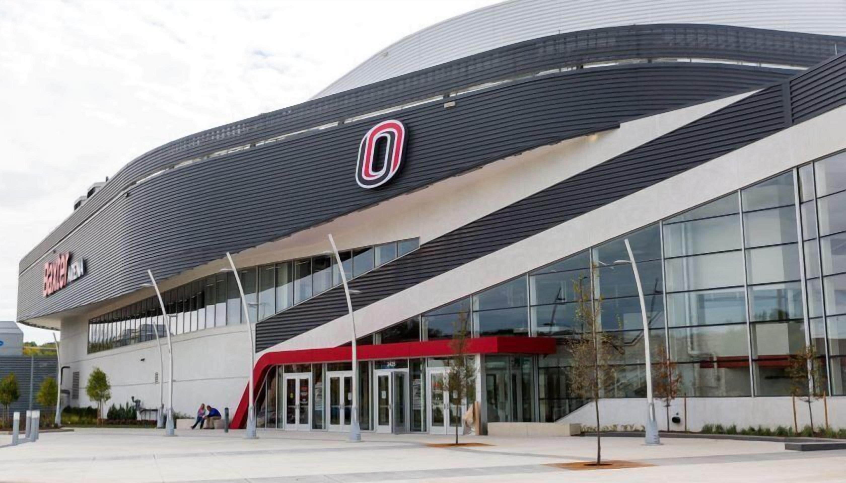 A modern building with a curved facade, large glass windows, and a prominent logo.