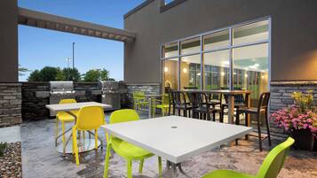 Un patio exterior con una parrilla, una zona de estar y vistas al interior a través de amplios ventanales.