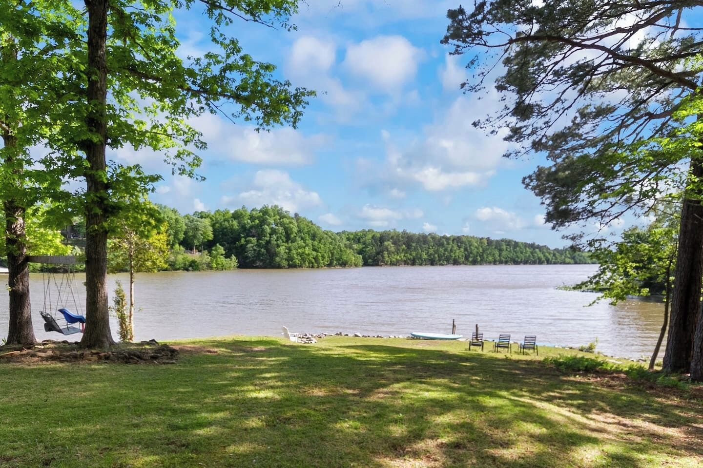 Une vue sur le lac, avec une zone herbeuse, des arbres et un quai où sont amarrés des bateaux.