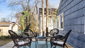 Un patio con cuatro mecedoras de mimbre, una mesita y un jarrón decorativo.