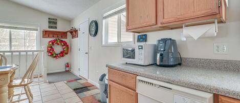 Una cucina con mobili in legno, un forno a microonde, una macchina per il caffè e una finestra.