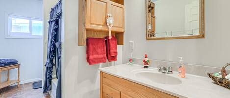 A bathroom with wooden cabinets, a white sink, and a large mirror.