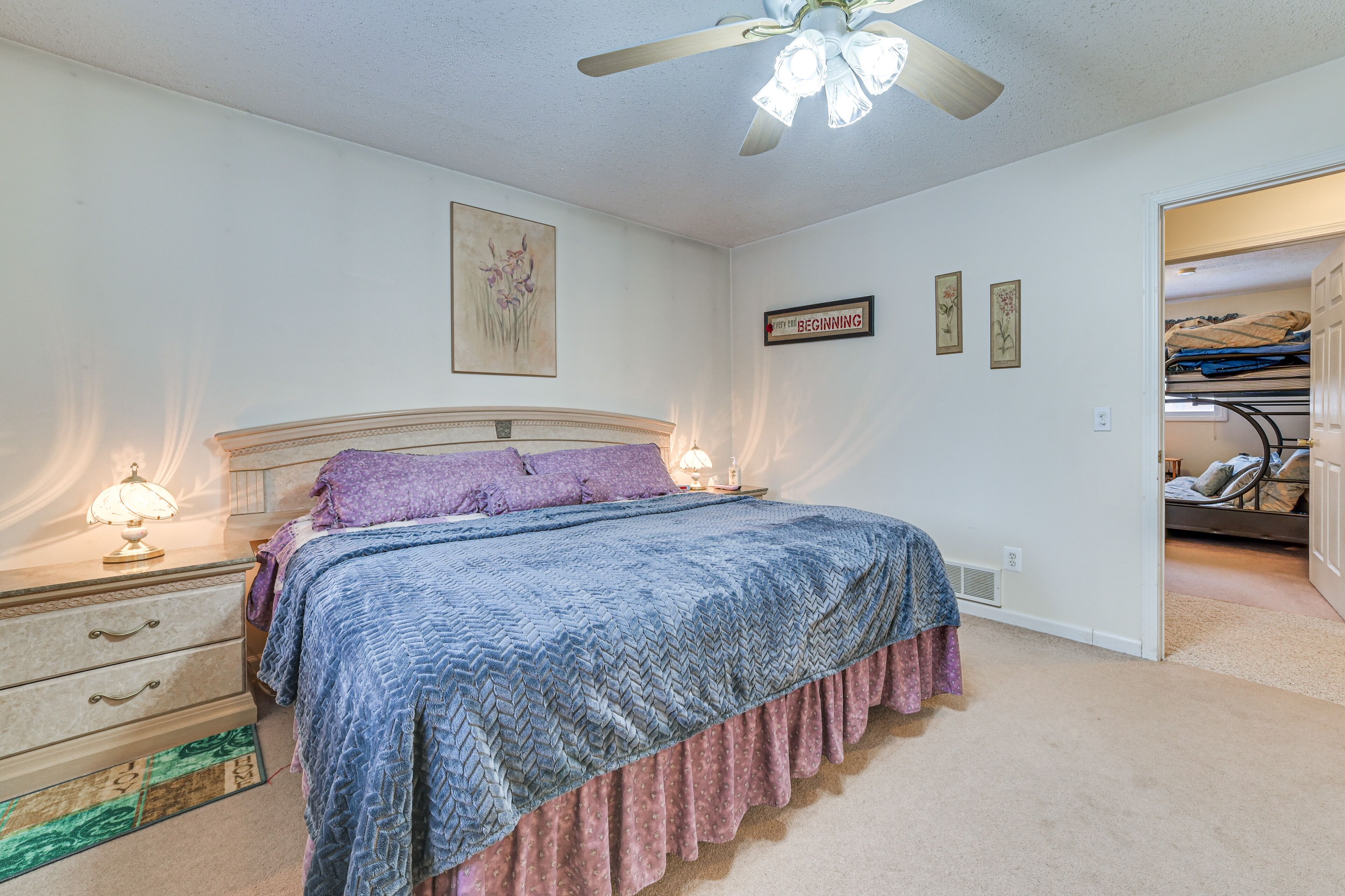 A bedroom with a bed, nightstands, a ceiling fan, and a closet.