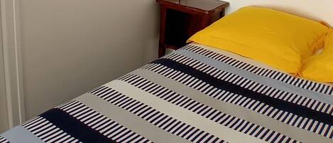 A bed with striped bedding, a red lamp, and two framed pictures on the wall.