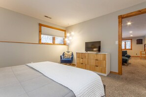 A bedroom with a bed, a dresser, a chair, a TV, and a window.