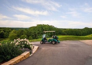 A golf cart on a paved path surrounded by lush greenery and flowering plants. - Modern spacious 4 bedroom retreat with 3 en-suites and all year round hot tub (Galena)