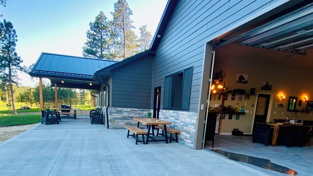 A modern building with a covered patio area, a stone wall, and a garage entrance.