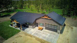 A modern house with a large garage, a covered patio, and a well-maintained lawn.