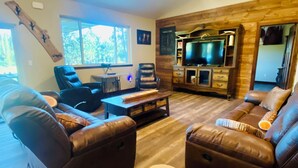 A modern living room with leather sofas, a coffee table, and a TV stand.