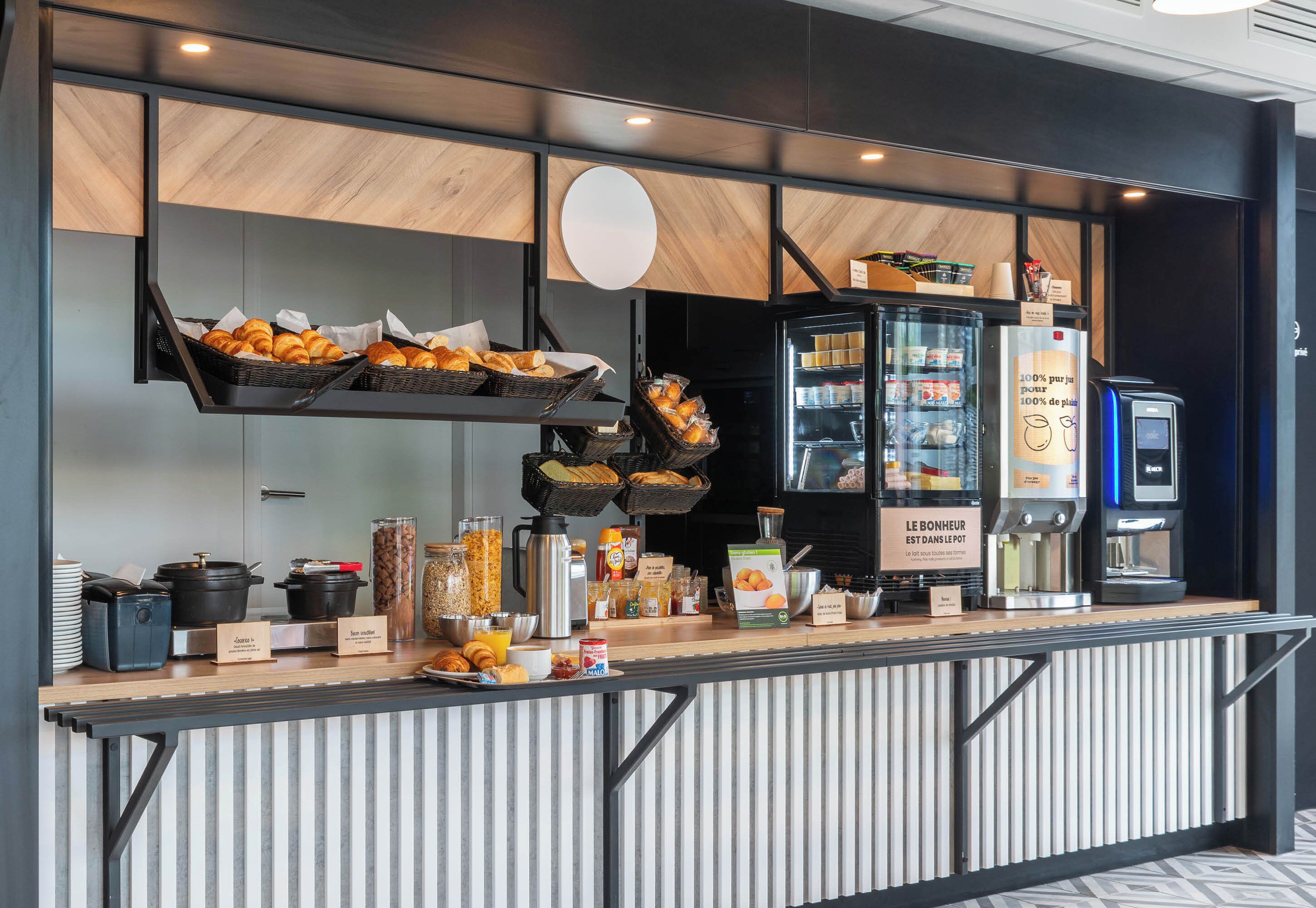 A breakfast bar with baskets of croissants, a coffee machine, and various breakfast items.