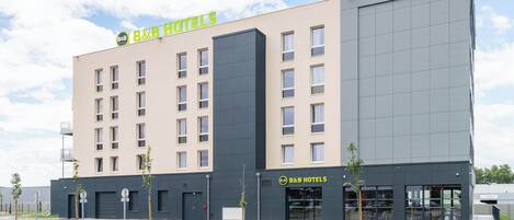 Un hotel B&B con fachada moderna, varios ventanales y un estacionamiento con espacios delimitados.