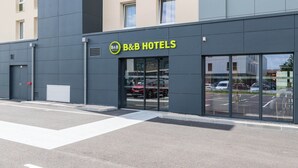 A B&B hotel with a modern facade, large glass entrance, and a parking lot visible through the windows. - B&B HOTEL Villefranche-sur-Saône Sud (Villefranche-sur-Saône)