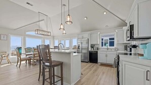 A spacious kitchen with white cabinetry, a central island, and pendant lighting.