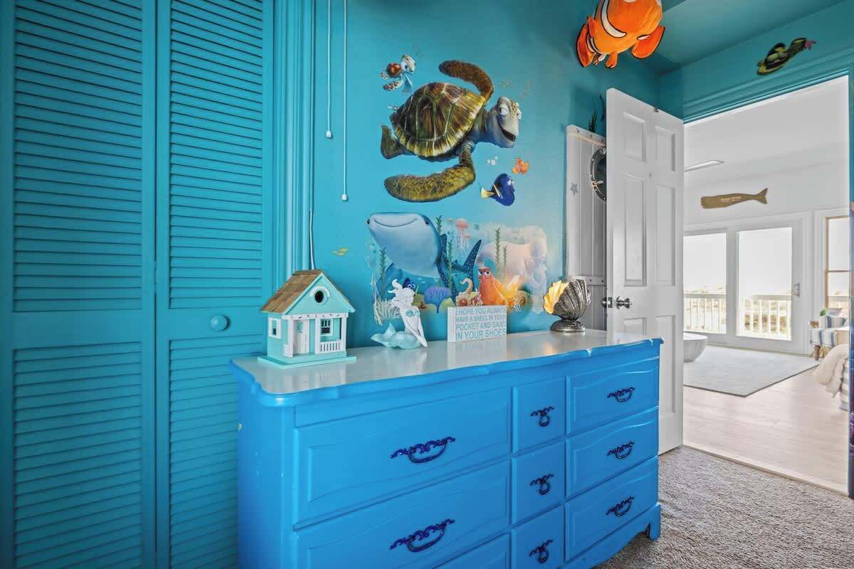 Una habitación con paredes color aguamarina, un aparador azul y un mural de criaturas marinas.