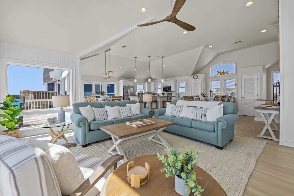 A spacious living area with light blue sofas, a wooden coffee table, and a ceiling fan.