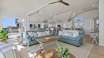 A spacious living area with light blue sofas, a wooden coffee table, and a ceiling fan.