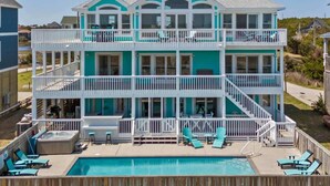 Ein zweistöckiges Strandhaus mit Pool, mehreren Balkonen und Außenmöbeln.