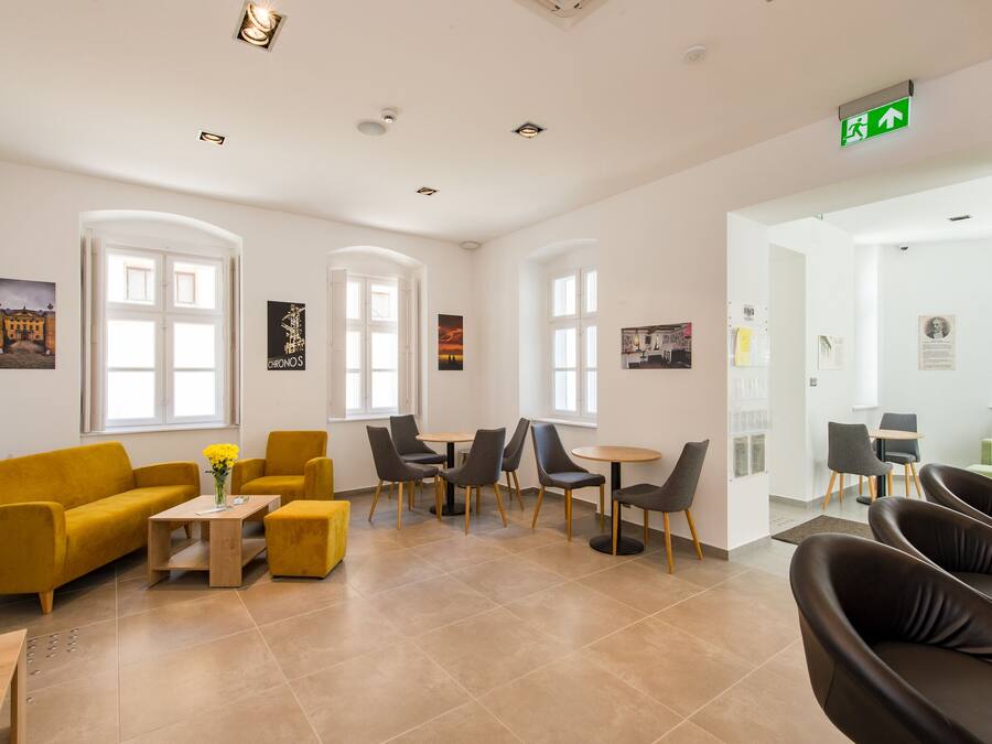 A modern waiting area with yellow and black seating, a wooden coffee table, and artwork on the walls.