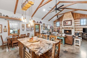 Relax in a spacious living area with a rustic stone fireplace, comfortable seating, and modern touches.