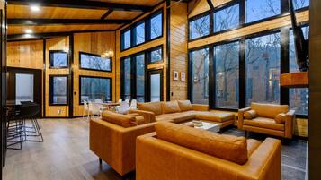 A spacious living area with a large sectional sofa, a dining table with chairs, and large windows offering views of the outside.