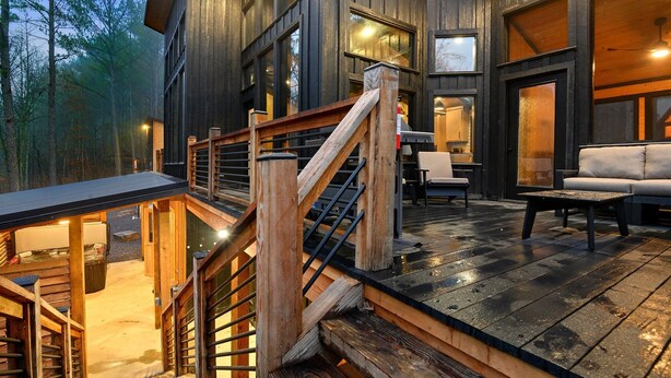 Una cabaña de madera con un balcón, asientos exteriores y una escalera.