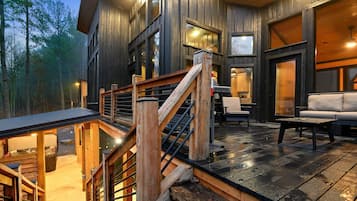 A wooden cabin with a deck, outdoor seating, and a staircase.