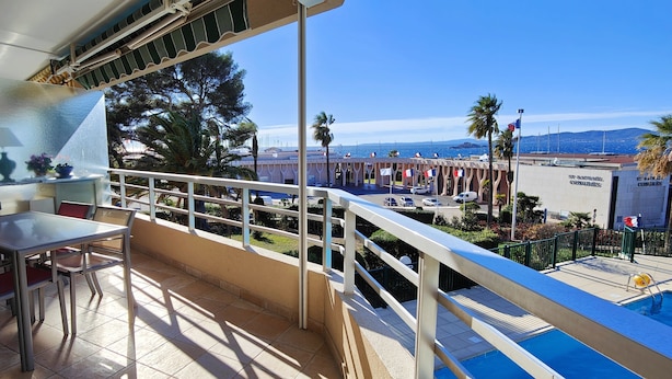 A balcony with a table and chairs, a pool, and a view of the sea and buildings. - 50 m² cocoon of Love with a common shared pool (Saint-Raphaël)