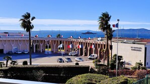 A building with multiple flags, a parking lot, and a view of the sea. - 50 m² cocoon of Love with a common shared pool (Saint-Raphaël)