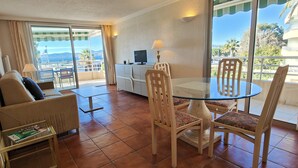 A hotel room with a balcony, a sofa, a glass table, and a TV. - 50 m² cocoon of Love with a common shared pool (Saint-Raphaël)