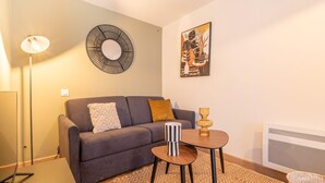 Una sala moderna con un sofá gris, una mesita redonda y una lámpara de pie.
