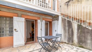 Un patio con una mesa, sillas, una puerta blanca y una escalera.