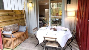 A wooden porch with a dining table set for two, a bench, and a door marked with the number 18. - Beautiful 3 rooms with terrace near the ocean (Moliets-et-Maa)