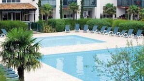 A hotel with a swimming pool, lounge chairs, and palm trees. - Beautiful 3 rooms with terrace near the ocean (Moliets-et-Maa)