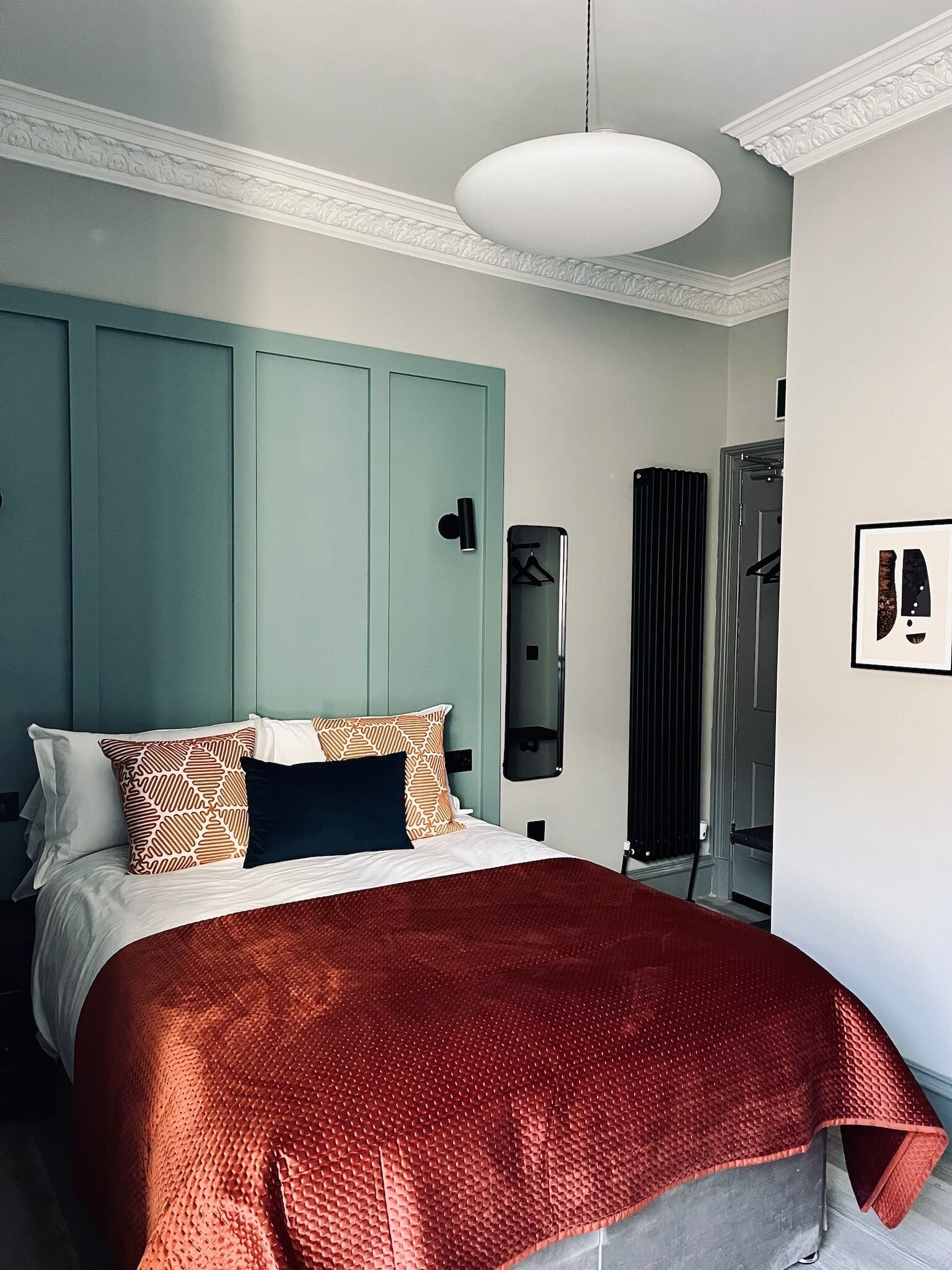 A bedroom with a bed, a wardrobe, a mirror, and a radiator.