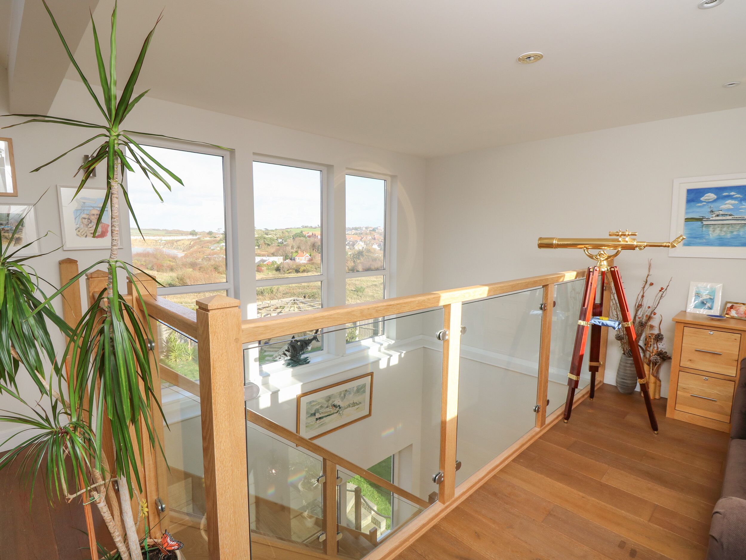 A spacious room with a balcony, large windows, and a telescope.