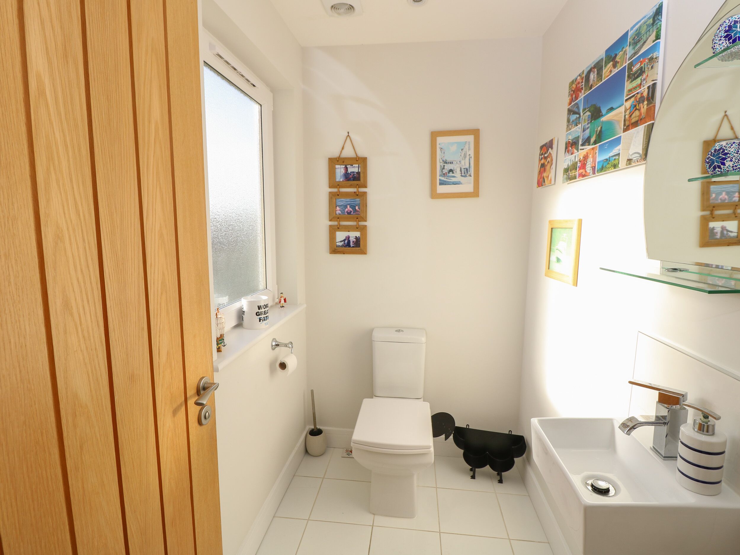 Une petite salle de bain comprenant des toilettes, un lavabo et une petite étagère où sont rangés les articles de toilette.