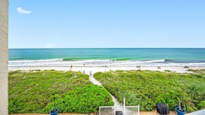 Vista sulla spiaggia con un sentiero che conduce all'acqua, immerso nel verde.