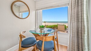 Un balcone con un tavolo e sedie in vetro, uno specchio rotondo e vista sulla spiaggia.