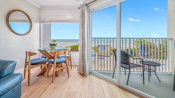 Un balcone con vista sul mare, un'area pranzo con tavolo e sedie, e un grande specchio a parete.